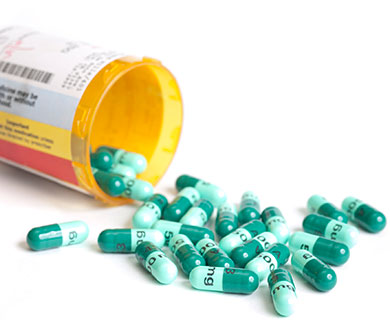 A pile of antibiotic capsules are spilling out a prescription bottle.