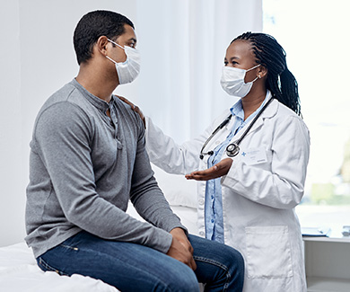 A masked patient consults with a masked physician.