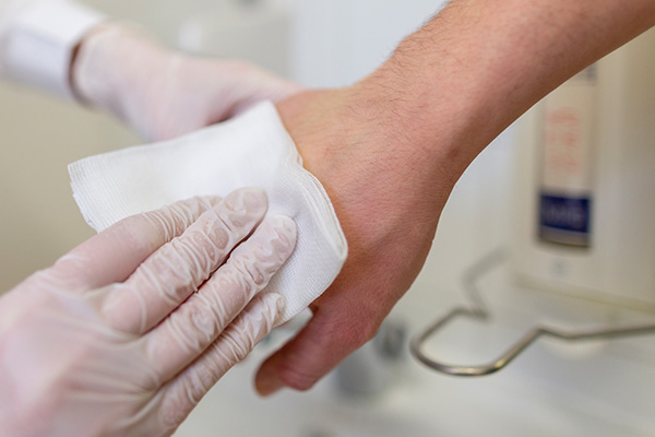 Medical professional wiping patient's hand to remove germs