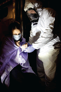 Picture of physician in Hazmat suit covering patient with blanket